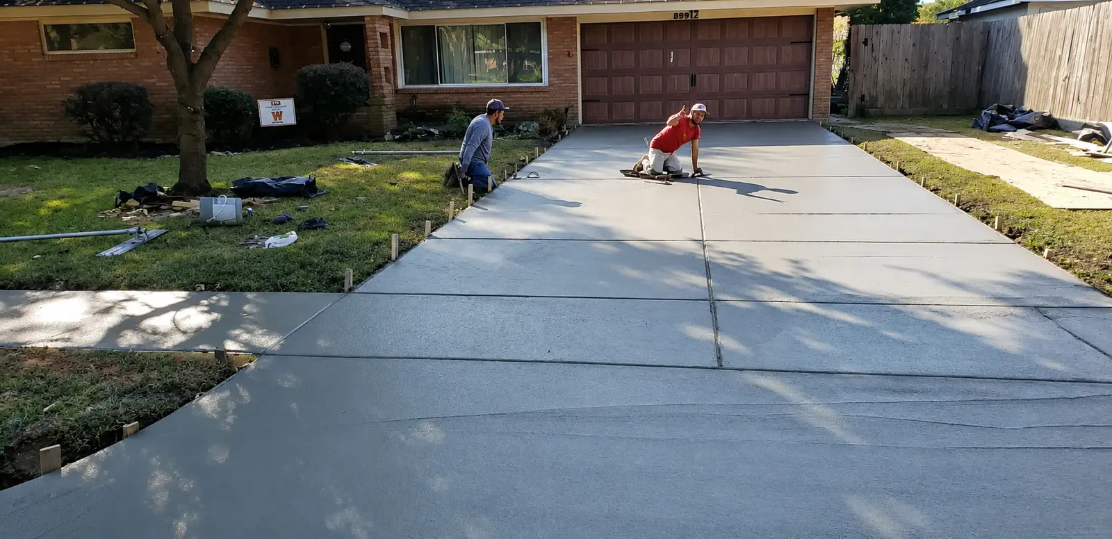 Crew finishing a newly poured concrete driveway